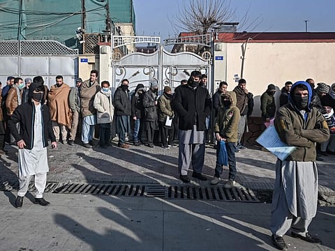 People queue to enter the passport office at a checkpoint in Kabul on December 19, 2021, after the Taliban government said they will resume issuing passports.