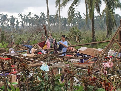 This photo taken on December 18, 2021 and received on December 19 from the Philippine Coast Guard (PCG) shows a resident drying her clothes on the ruins of a home in Del Carmen town in Surigao del Norte province, days after Super Typhoon Rai devastated the province.