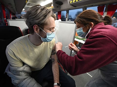 A member of the public receives his vaccine inside a NHS (National Health Service) bus parked outside an Asda Supermarket in the town of Farnworth, near Manchester in north-west England on December 20, 2021, as the booster rollout accelerates in England.