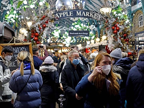 Shoppers, some wearing face coverings to combat the spread of Covid-19, walk past stalls and shops in the Apple Market in Covent Garden on the last Saturday for shopping before Christmas, in central London on December 18, 2021.