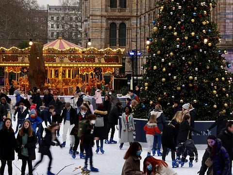 People ice skate around the Christmas tree at the Natural History Museum, in London, on December 21, 2021.