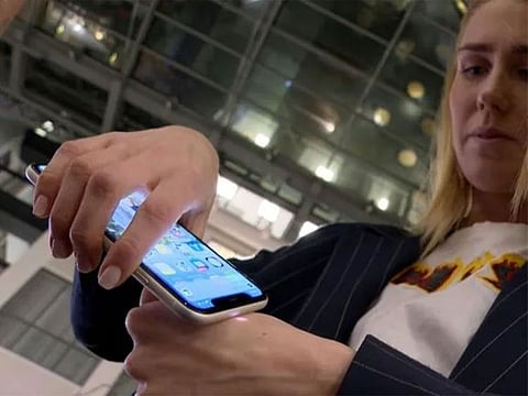 Amanda Back uses her smartphone to scan a microchip implanted in her hand to reveal her health pass