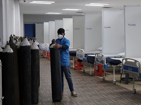 A worker handles an oxygen cylinder at a COVID-19 isolation centre being prepared as a precautionary measure due to Omicron variant at the Commonwealth Games (CWG) Village Sports Complex in New Delhi, on Tuesday.