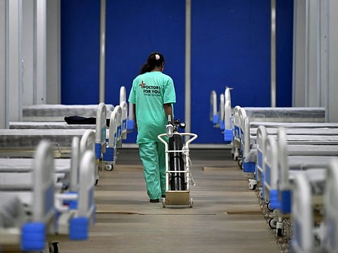 A medic carries an oxygen cylinder at Commonwealth Games Village isolation centre in view of rising Omicron cases, in New Delhi, on Thursday.