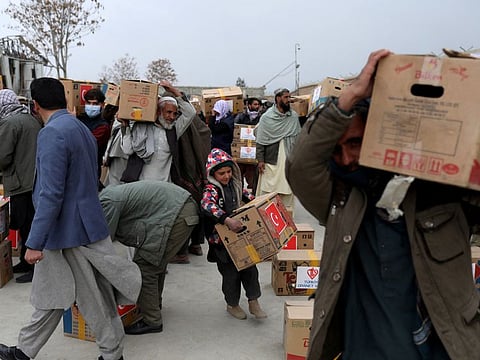 Afghans carrying packages distributed by a Turkish humanitarian aid group, leave a distribution centre in Kabul, Afghanistan.