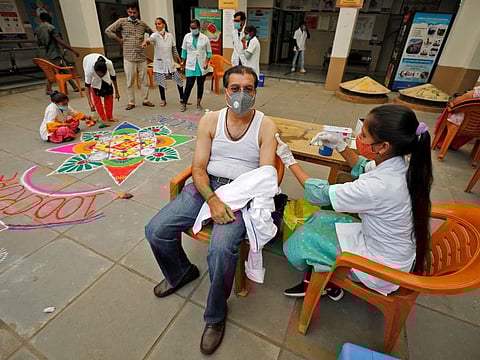 A healthcare worker gives a dose of the Covishield vaccine as others decorate the vaccination centre in Ahmedabad.