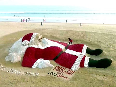 Artist Sudarsan Pattnaik creates a 50ft long, 28ft wide sand sculpture of Santa Claus with about 5,400 red roses and other flowers in Puri.