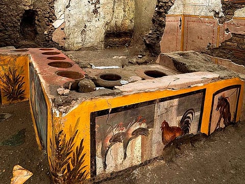 This picture released on December 26, 2020 by the Pompei Press Office shows a thermopolium, a sort of street "fast-food" counter in ancient Rome, that has been unearthed in Pompei, decorated with polychrome motifs and in an exceptional state of preservation