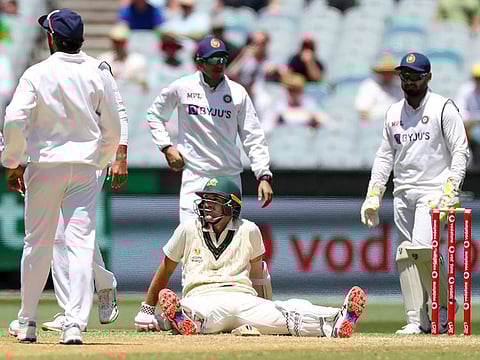 Australia's Joe Burns sits on the pitch as he awaits a video review during play on day three of the second cricket test between India and Australia at the Melbourne Cricket Ground.