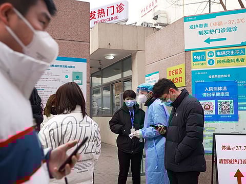 A medical staff member gives COVID-19 advice outside a nucleic testing site at a hospital in Beijing, China.