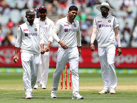 Umesh Yadav, centre, reacts after suffering an injury while bowling during play on day three.