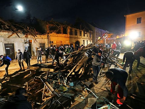 People clean debris from a street after an earthquake, in Petrinja, Croatia December 29, 2020.