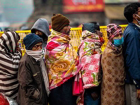 People line up to get free breakfast outside a temple during a cold winter morning in New Delhi on December 31, 2020. The authorities have imposed a curfew in Delhi to check the spread of COVID-19.