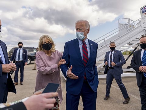 Jill Biden moves her husband, Democratic presidential candidate former Vice President Joe Biden, back from members of the media as he speaks outside his campaign plane in New Castle, Del., on Oct. 5, 2020.