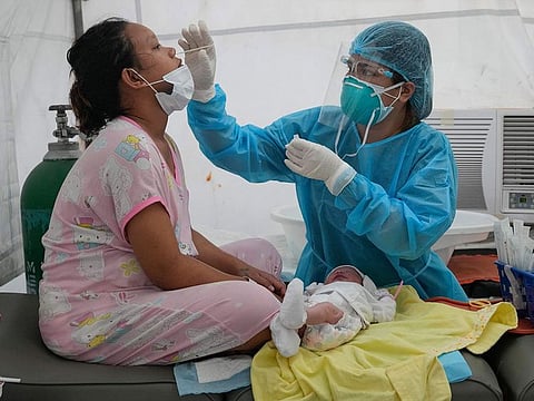 Medical Technologist Erika Alvarado performs a COVID-19 test on a patient who just delivered a baby outside a hospital in Manila, Philippines .