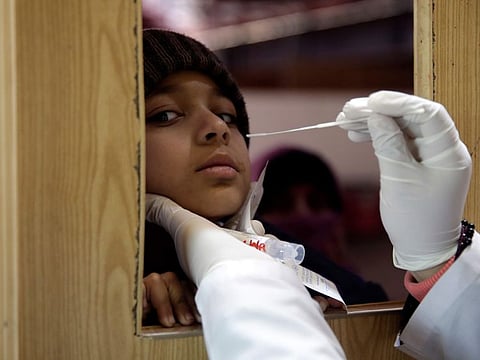 A Pakistani lab technician takes a sample with a swab to test for the coronavirus at the PIMS Hospital, in Islamabad, Pakistan, Monday, Jan. 3, 2022.