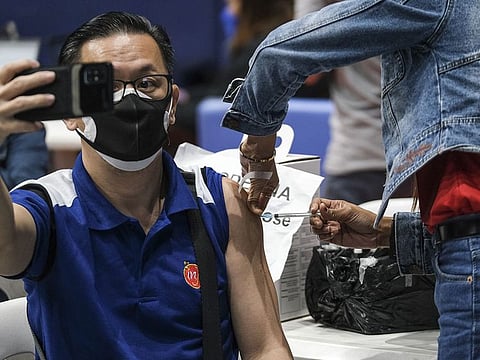 A member of the public takes a selfie while receiving a booster dose of the Moderna Inc. Covid-19 vaccine at a vaccination site inside a gymnasium in San Juan City, Metro Manila, the Philippines.