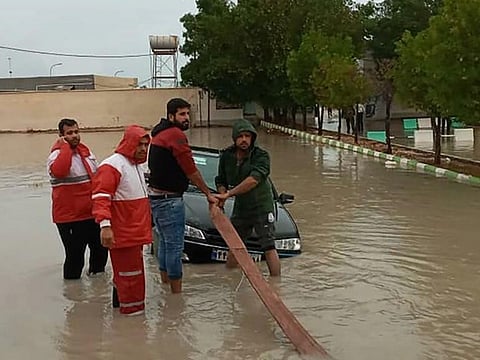 A handout picture made available by the Iranian Red Crescent shows members helping tow a vehicle stuck in floodwaters in Hormozgan Province in the country’s south.