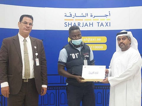 Abraham Airaodion (centre) was honoured by Khalid Al Kindi (R), executive director of Sharjah Taxi, in appreciation of his honesty