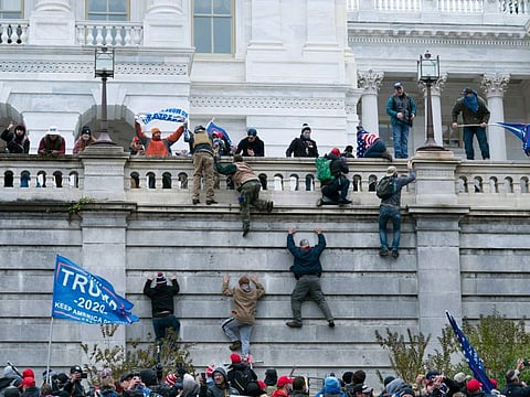 Supporters of President Donald Trump climb the west wall of the the US Capitol on Jan. 6, 2021, in Washington.