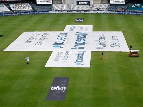 South African reserve umpire Bongani Jele (left) walks off the field after consulting with ground staff as rain has delayed start of play during the fourth day of the second Test between South Africa and India at The Wanderers Stadium in Johannesburg today.