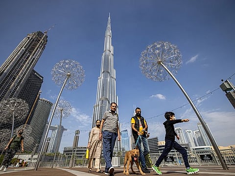Pedestrians walk along a promenade near the Burj Khalifa skyscraper, in Dubai
