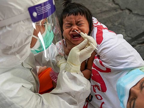 A health worker from Zendai organisation in personal protective equipment (PPE) takes a swab sample from a girl for a rapid antigen test amid the coronavirus disease (COVID-19) outbreak, in Bangkok, Thailand, January 5, 2022.