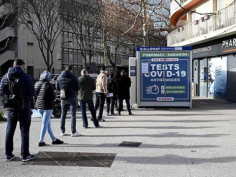 People queue outside a pharmacy to receive COVID-19 antigen tests in Marseille, southern France.
