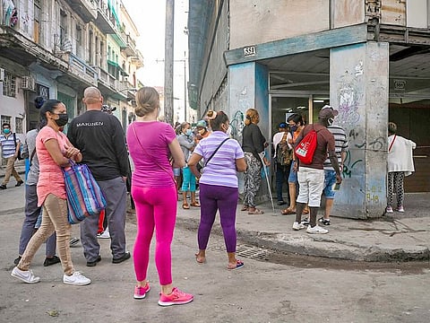Cubans queue to by food outside a store in Havana.