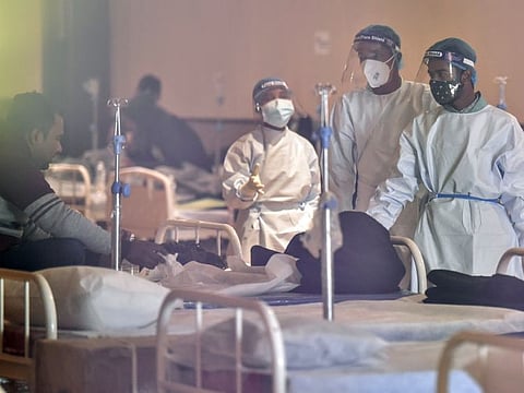Healthcare workers interact with a COVID-19 patient inside a temporarily converted isolation ward at a banquet hall in New Delhi on Tuesday.