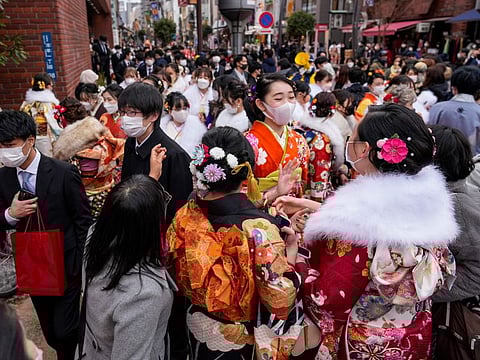 Women and men clad in Japan's traditional kimono outfits and business suits, who have just turned and will be 20 years old this year, gather outside a public hall after attending a Coming of Age Day ceremony on January 10, 2022, in Tokyo.