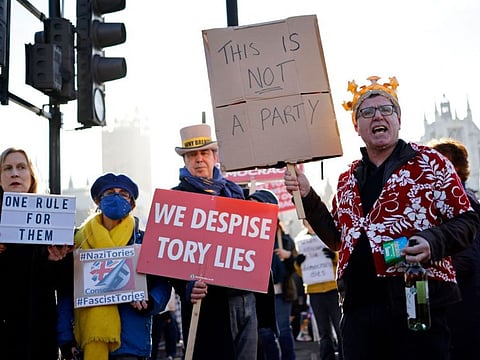 Demonstrators hold placards as they protest near the House of Commons, where Britain's Prime Minister was taking part in the weekly session of Prime Minister Questions (PMQs) in central London on January 12, 2022.