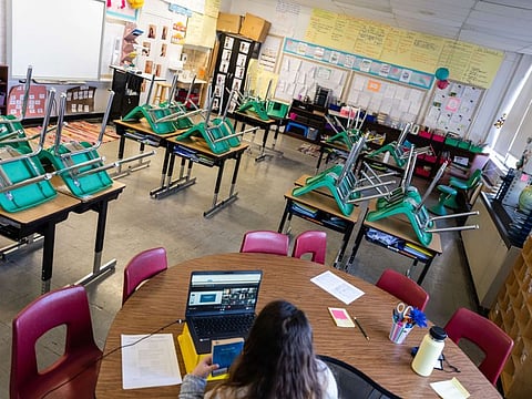 A teacher interacts with students virtually while sitting in an empty classroom during a period of Non-Traditional Instruction (NTI) at Hazelwood Elementary School on January 11, 2022 in Louisville, Kentucky.