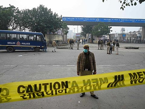 Delhi police personnel stand guard after the National Security Guard (NSG) carried out a controlled explosion of an Improvised Explosive Device (IED) found at East Delhi's Ghazipur Flower Market in New Delhi on January 14, 2022.