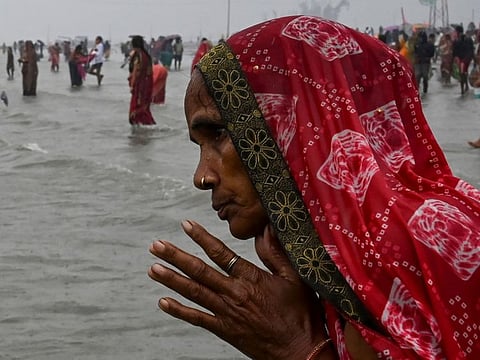A Hindu pilgrim prays as she takes a holy dip at the confluence of Ganges and the Bay of Bengal during the Gangasagar Mela on the occasion of Makar Sankranti, a day considered to be of great religious significance in Hindu mythology, at Sagar Island, around 150 kms south of Kolkata on January 14, 2022.