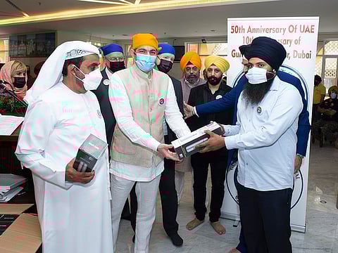 A visitor (R) receives a flask in the new community drive launched during 10th anniversary celebrations of Guru Nanak Darbar Gurudwara in Dubai on Sunday