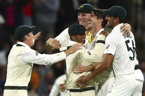 Australia's Pat Cummins celebrates with Usman Khawaja and other teammates after taking England's last wicket of the match and series during their Ashes cricket Test in Hobart, Australia.