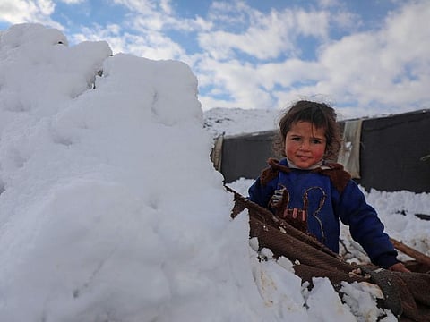 A child plays with snow at a camp for internally displaced people in the town of Raju in the rebel-controlled northern countryside of Syria's Aleppo province on January 19, 2022.