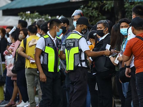 Transport authority personnel check COVID-19 vaccination cards of people at a bus station in Quezon City, suburban Manila on January 18, 2022.