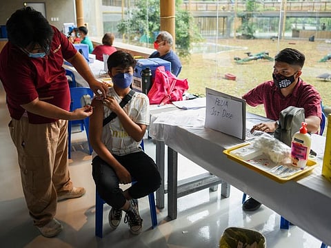 A health worker inoculates a boy with a Pfizer coronavirus disease (COVID-19) vaccine, at Manila Zoo, in Manila, Philippines, January 19, 2022.