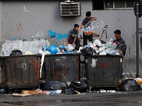 Boys scavenge in garbage dumpsters for valuables and metal cans to sell, in Beirut.