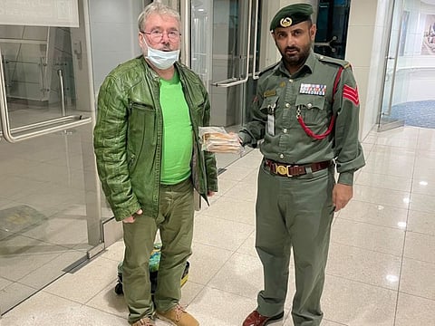 A Dubai Police officer hands over the lost cash to its owner, Siegfried Tellbach - a traveller from Germany.