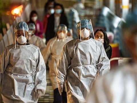 Health officials wearing personal protective equipment (PPE) outside the Yat Kwai House building placed under lockdown at the Kwai Chung Estate public housing complex in Hong Kong, China, on Friday, Jan 21, 2022. Hong Kong is locking down about 2,700 residents for five days, the first time its closed off an apartment complex for more than 48 hours, in the hope of containing a superspreader event that has already led to 16 people testing positive for Covid.