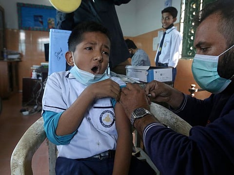 A student receives a doze of Pfizer COVID-19 vaccine from a health worker at a school in Karachi, on January 20, 2022. Vaccination of children over the age of 12 has been made mandatory to attend the schools and children under 12 will attend schools with 50% attendance.