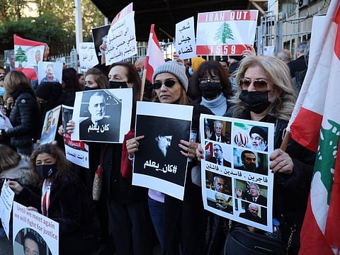 Activists and relatives of victims of the August 4, 2020 Beirut port explosion hold posters of Hezbollah leader Hassan Nasrallah (R) and Wafiq Safa, a top Hezbollah security official, with a slogan in Arabic that reads: "He knew," during a sit-in outside the Justice Palace, a government building affiliated with the judiciary, in the Lebanese capital on January 17, 2022.