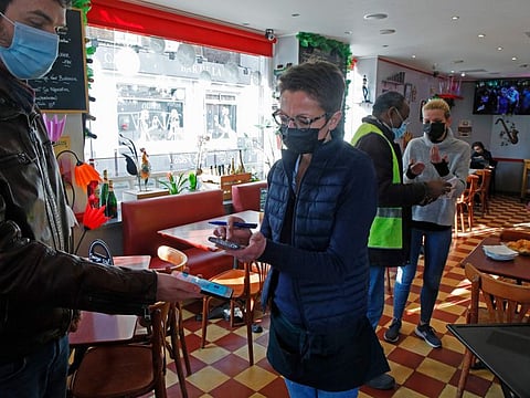 A waiter checks clients' vaccine passes at a restaurant in Lille, northern France, Monday, Jan. 24, 2022. Unvaccinated people are no longer allowed in France's restaurants, bars, tourist sites and sports venues, as a new law came into effect Monday requiring a "vaccine pass" that is central to the government's anti-virus strategy.