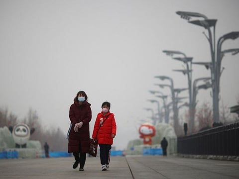 People walk near the closed loop "bubble" surrounding venues of the Beijing 2022 Winter Olympics on a hazy day in Beijing, China, January 24, 2022.