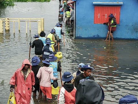 People walk through flood water after several houses were affected by rising water following heavy rains in Antananarivo.