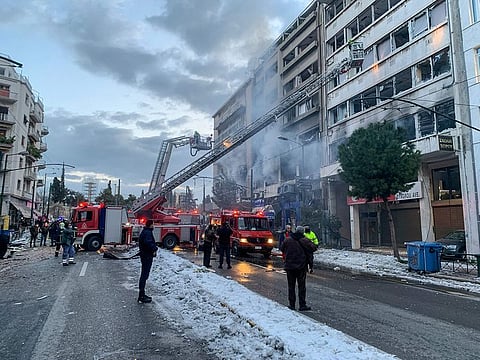 Firefighters use aerial ladders to look for anyone possibly trapped inside damaged buildings following an explosion in central Athens, on Wednesday, January 26, 2022.