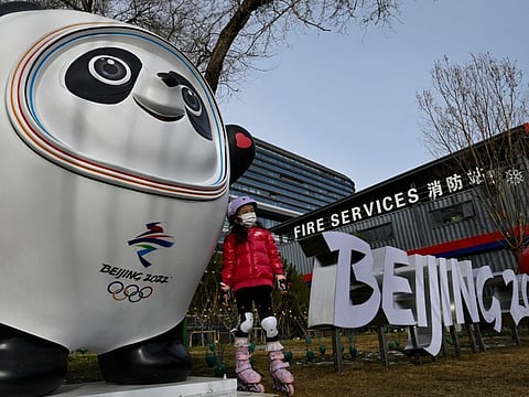 A girl poses for photos next to an installation of Bing Dwen Dwen, mascot of the Beijing 2022 Olympic Games, displayed on a street in Beijing.